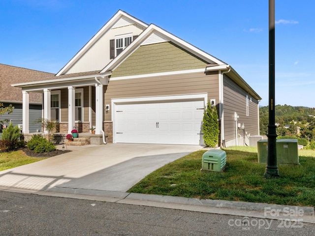 craftsman house with a porch, concrete driveway, a front lawn, and an attached garage