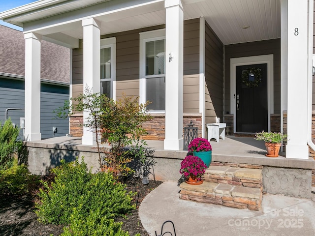 entrance to property featuring stone siding and a porch