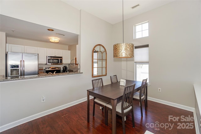 dining room featuring dark wood-style floors, visible vents, and baseboards