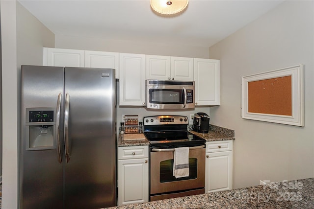 kitchen with appliances with stainless steel finishes, dark stone counters, and white cabinetry