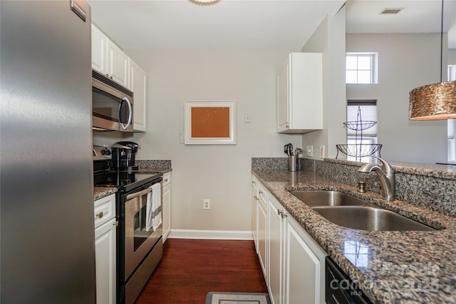 kitchen featuring appliances with stainless steel finishes, dark stone countertops, a sink, and visible vents