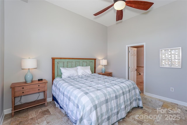 bedroom featuring ensuite bathroom, ceiling fan, stone tile flooring, and baseboards