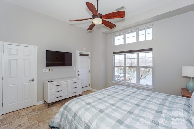 bedroom with visible vents, a towering ceiling, a ceiling fan, stone finish flooring, and baseboards