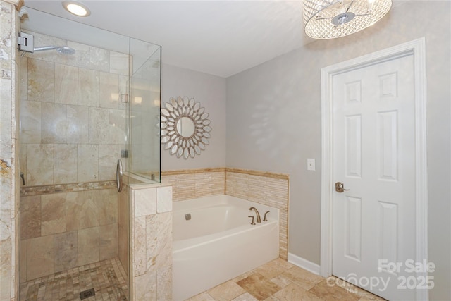 bathroom with a shower stall, baseboards, and a bath