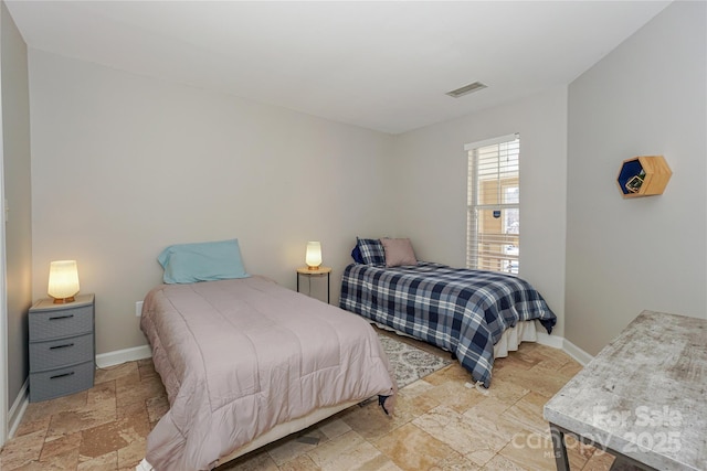 bedroom with visible vents, baseboards, and stone tile flooring