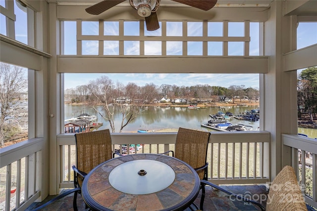 sunroom / solarium featuring a water view and ceiling fan