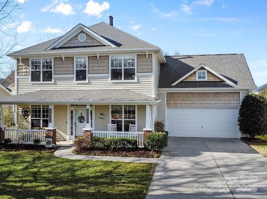 view of front facade with a front lawn, an attached garage, covered porch, and driveway