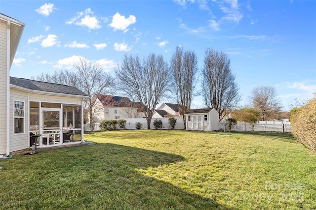 view of yard with an outbuilding, a fenced backyard, a shed, and a sunroom