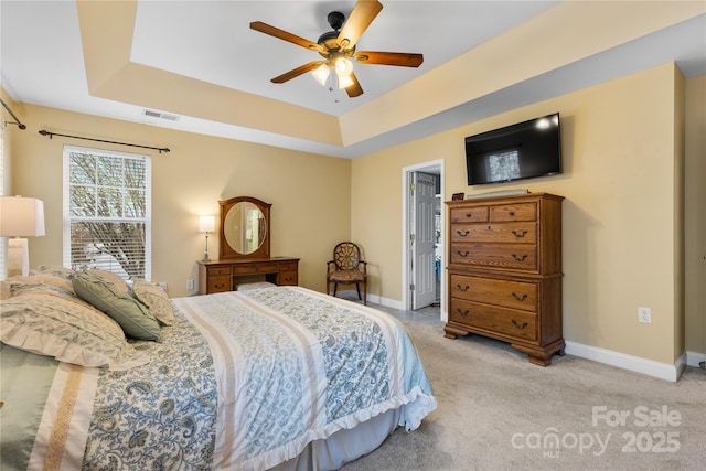 bedroom featuring light carpet, visible vents, a raised ceiling, and baseboards