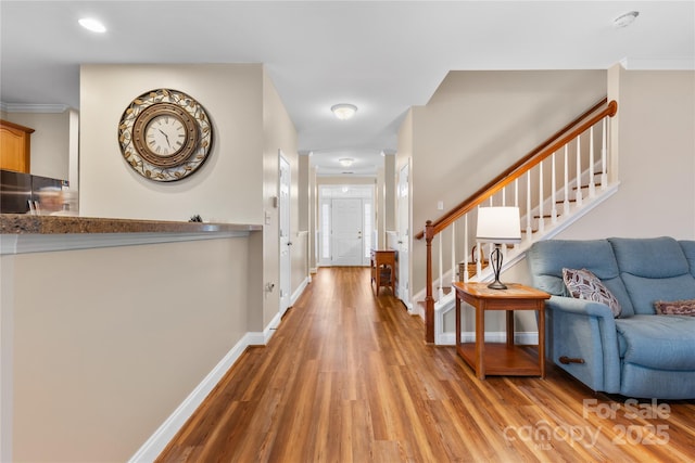 entrance foyer with light wood-style flooring, crown molding, stairs, and baseboards