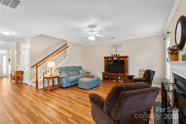 living area featuring visible vents, plenty of natural light, light wood-style flooring, and stairs