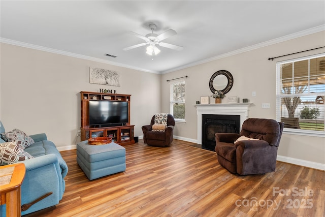 living area featuring crown molding, a fireplace with flush hearth, and wood finished floors