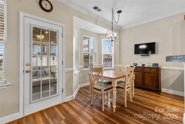 dining area with visible vents, an inviting chandelier, wood finished floors, and crown molding