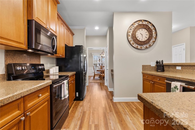 kitchen featuring brown cabinets, black appliances, light wood-style floors, decorative backsplash, and baseboards