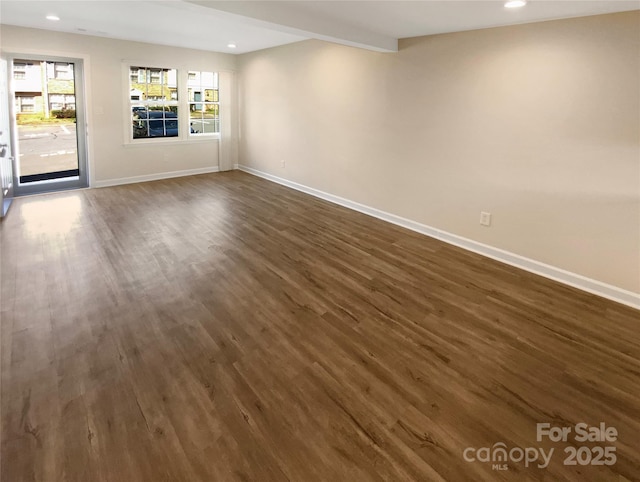 empty room with recessed lighting, beam ceiling, dark wood finished floors, and baseboards