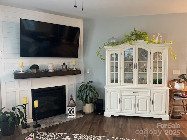 living area with a fireplace and dark wood-style flooring