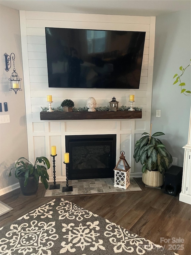 interior details with wood finished floors and a glass covered fireplace