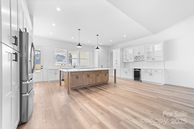 kitchen with wine cooler, a spacious island, white cabinets, stainless steel refrigerator with ice dispenser, and decorative light fixtures