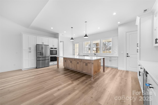 kitchen with light countertops, appliances with stainless steel finishes, a spacious island, and hanging light fixtures