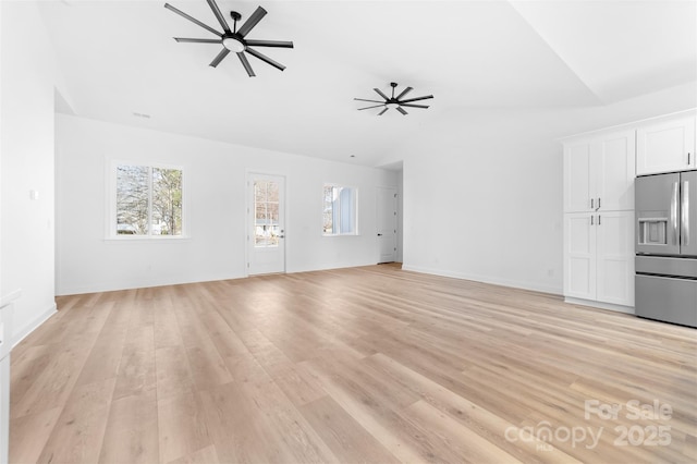 unfurnished living room featuring light wood-type flooring, ceiling fan, baseboards, and vaulted ceiling