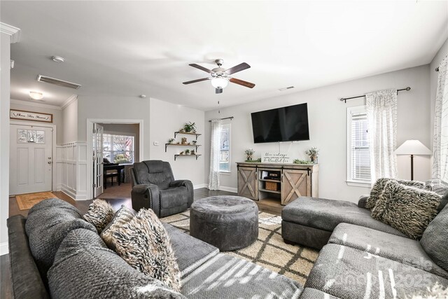 living area featuring a ceiling fan, baseboards, visible vents, and wood finished floors