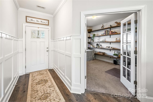 interior space with visible vents, a wainscoted wall, dark wood-style floors, ornamental molding, and a decorative wall