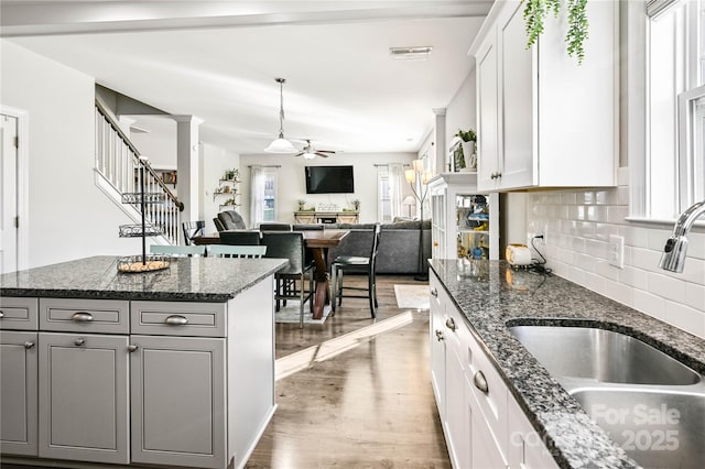 kitchen with decorative columns, tasteful backsplash, a ceiling fan, gray cabinetry, and a sink