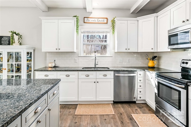 kitchen featuring appliances with stainless steel finishes, dark wood-style flooring, a sink, and beamed ceiling