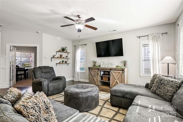 living room with ceiling fan, wood finished floors, visible vents, and baseboards