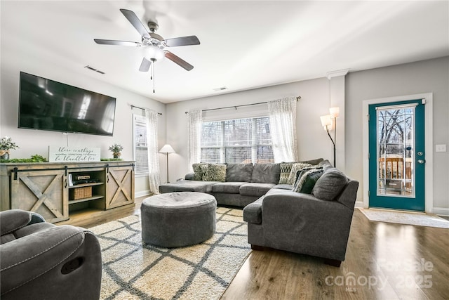 living area with baseboards, visible vents, and wood finished floors