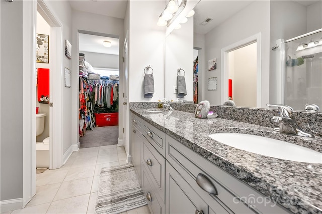 full bath featuring double vanity, visible vents, a spacious closet, a shower stall, and a sink