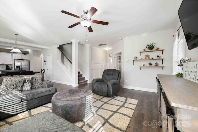 living area with ceiling fan, arched walkways, visible vents, stairway, and dark wood finished floors