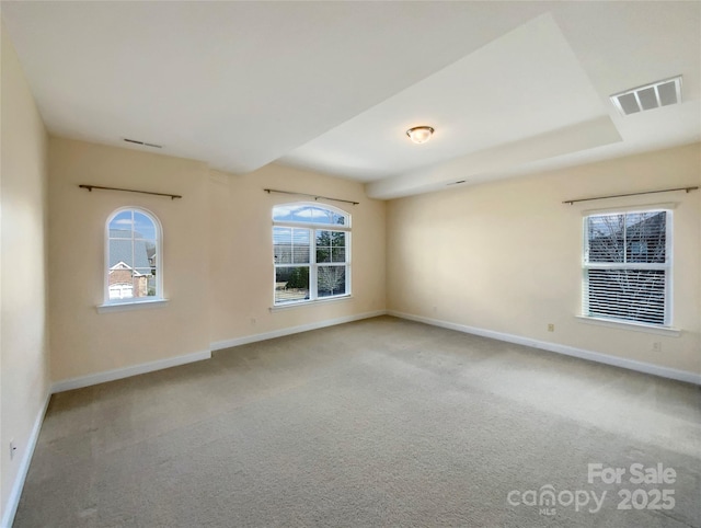 spare room with plenty of natural light, carpet, visible vents, and baseboards