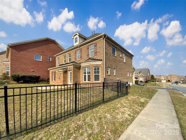 view of side of property featuring a yard, fence, and brick siding