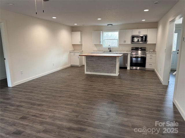 kitchen with white cabinets, dark wood-type flooring, stainless steel appliances, light countertops, and a sink