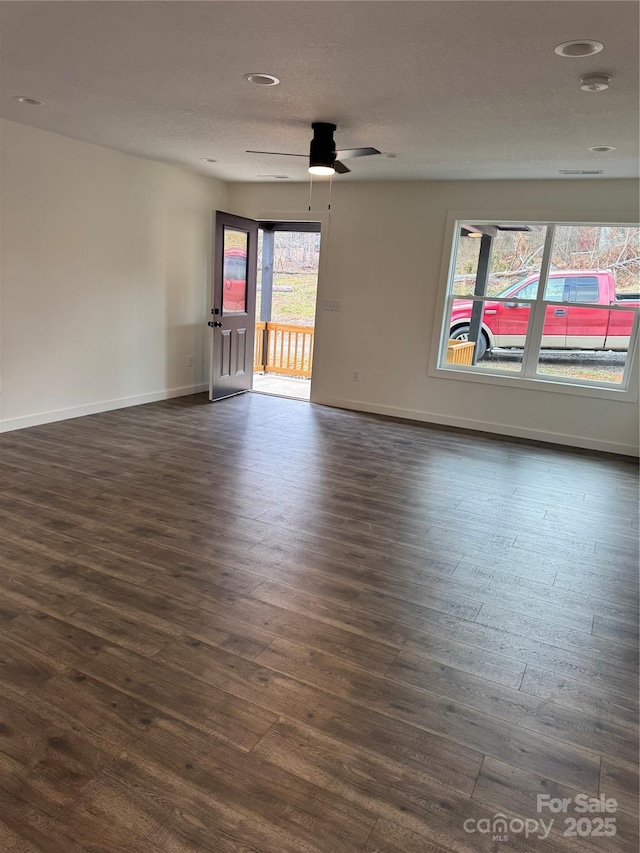 spare room featuring dark wood-type flooring, ceiling fan, a textured ceiling, and baseboards