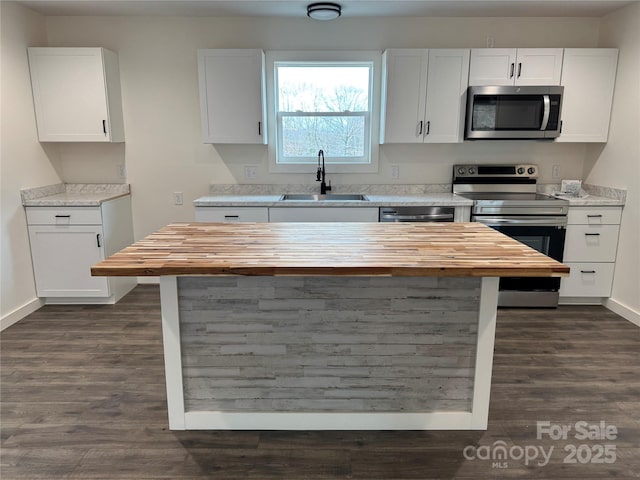 kitchen featuring appliances with stainless steel finishes, butcher block counters, and white cabinetry