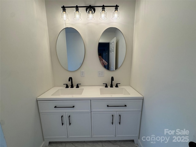 full bath featuring marble finish floor, double vanity, and a sink