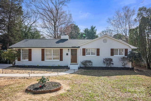 ranch-style house featuring a shingled roof, brick siding, a chimney, and a front lawn