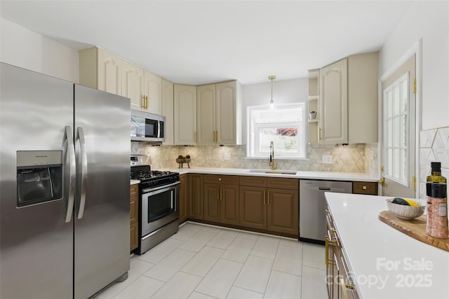 kitchen featuring light countertops, stainless steel appliances, a sink, cream cabinets, and backsplash