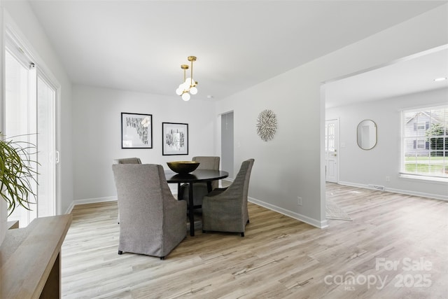 dining area featuring light wood finished floors, baseboards, and a chandelier