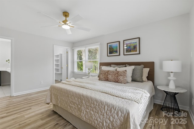 bedroom with ensuite bathroom, baseboards, wood finished floors, and a spacious closet