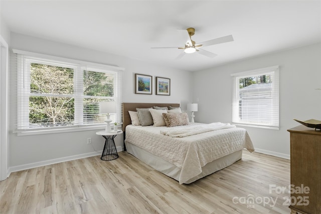 bedroom with light wood-style flooring, baseboards, and multiple windows