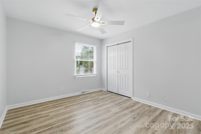 unfurnished bedroom with light wood-type flooring, baseboards, visible vents, a ceiling fan, and a closet