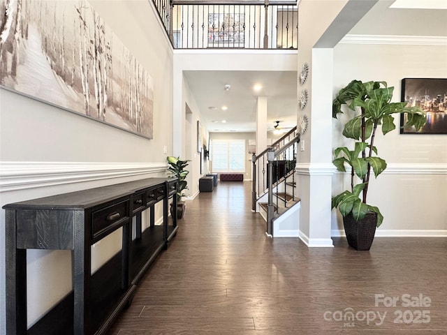 hall featuring baseboards, a high ceiling, stairway, and dark wood finished floors