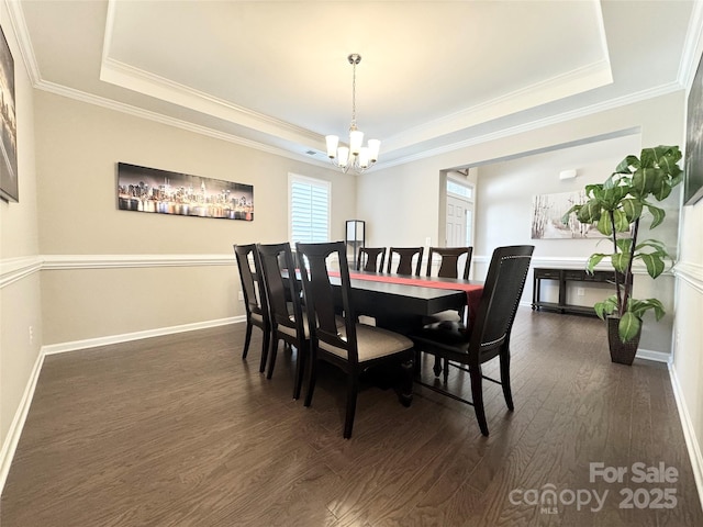 dining room with baseboards, a raised ceiling, dark wood-style floors, crown molding, and a chandelier