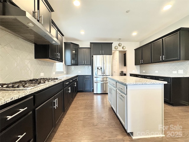 kitchen with gas cooktop, wood finished floors, stainless steel fridge, and under cabinet range hood