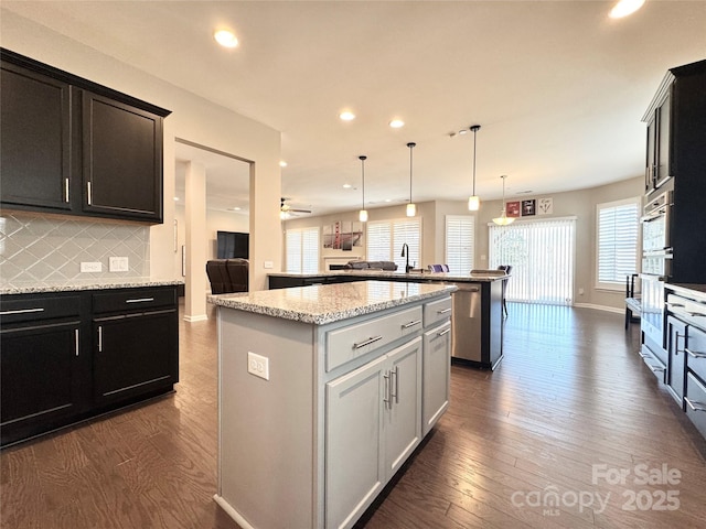 kitchen featuring dark wood-style floors, a center island, backsplash, and a peninsula