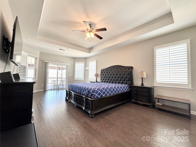 bedroom with access to exterior, a tray ceiling, wood finished floors, and ornamental molding