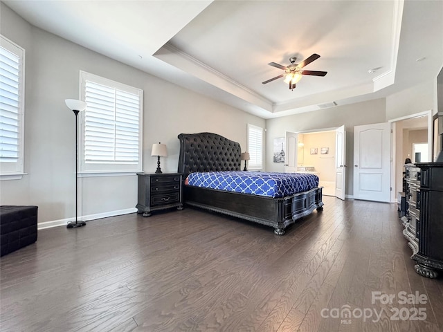 bedroom with a raised ceiling, dark wood finished floors, and baseboards